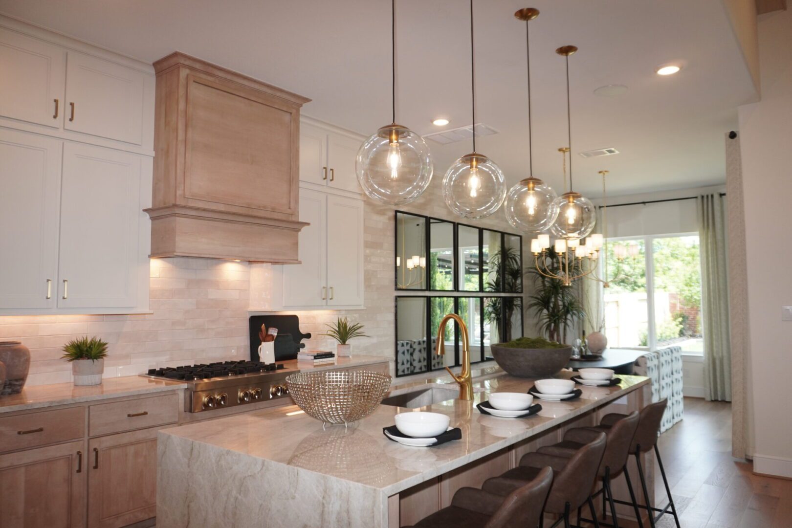 A kitchen with marble counter tops and hanging lights.