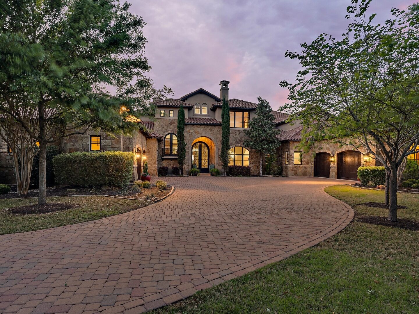 A modern home in Austin, Texas with a brick driveway leading to the entrance at dusk.