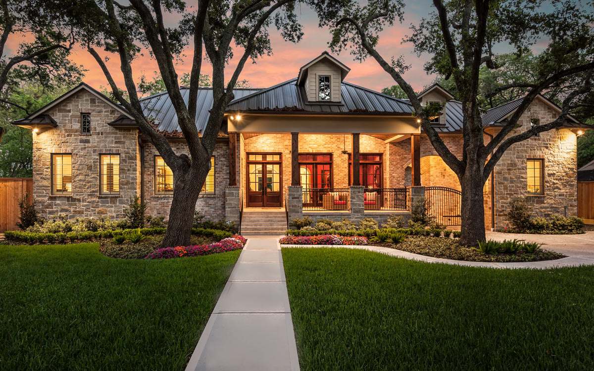 A charming Austin home with a stone front and lush lawn, perfect for those seeking Texas ranch homes for sale. Enjoy the tranquility of dusk as you relax in this picturesque property.