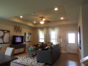 A living room with a tv and a ceiling fan built by Texas builders.