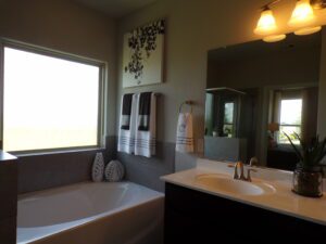 A bathroom with a tub, sink and window built by Texas builders.