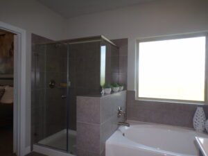 A bathroom with a glass shower stall and a tub, expertly designed by Texas builders.