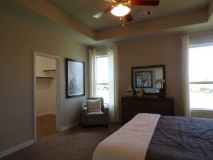 A bedroom with a ceiling fan and a dresser built by Texas builders.