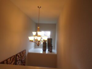 A hallway with a light fixture and vases designed by Texas builders.