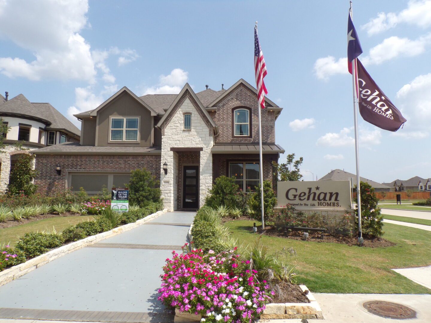 A new two-story house with a landscaped front yard, an American flag, and a Texas builders sign prominently displayed.