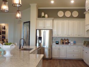 Modern kitchen with white cabinetry, stainless steel appliances, marble countertops, and pendant lighting designed by Texas builders.
