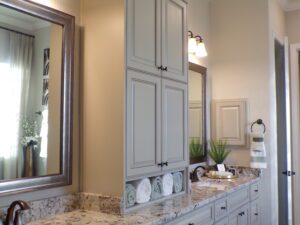 Elegant bathroom interior featuring a large mirror, granite countertop with dual sinks, and gray cabinetry by Texas builders.