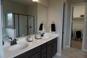 A bathroom with two sinks and a walk in shower built by Texas builders.