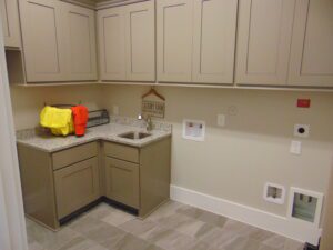 A modern kitchen corner featuring beige cabinets, a dual sink, granite countertops, and tiled flooring by Texas builders.