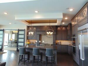 Modern kitchen interior with gray cabinetry, a central island with bar stools, pendant lights, and stainless steel appliances designed by Texas builders.