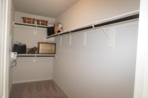 An empty walk-in closet featuring shelves, hanging rods, and organized storage baskets, constructed by Texas builders.