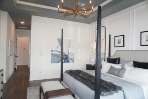 A bedroom designed by Texas builders featuring a four poster bed and a chandelier.