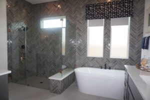 A bathroom with gray tile and a glass shower stall built by Texas builders.