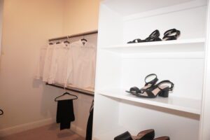 A closet with white shirts and black shoes, built by Texas builders.