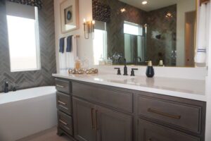 A bathroom with gray cabinets and a large mirror built by Texas builders.