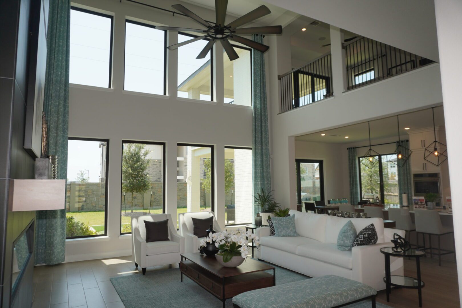 A spacious living room with large windows and a ceiling fan, perfect for enjoying the Texas breeze.