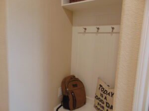 A backpack is sitting on a shelf in a closet.