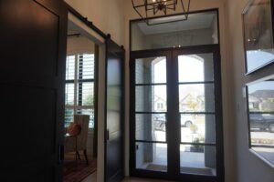A hallway with black doors and a Texas builders glass door.