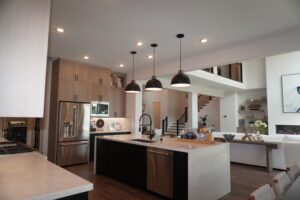 Modern kitchen interior featuring a central island, wooden cabinets, stainless steel appliances, and pendant lighting designed by Texas builders.