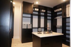 Modern walk-in closet with black cabinetry, a central island, and horizontal striped walls, crafted by Texas builders.