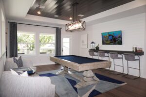 Modern game room designed by Texas builders, featuring a pool table, bar seating area, and a cozy lounging nook, decorated with neutral tones and vibrant wall art.