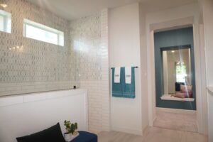 A bathroom with a blue tiled wall and white tiled floor, built by Texas builders.