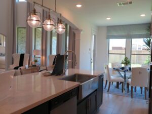 Modern kitchen and dining area with pendant lighting, a kitchen island, and large windows, crafted by Texas builders.