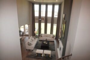 Overhead view of a modern living room with beige sofas, a black coffee table, gray rug, pendant lights, and tall curtains in Texas.