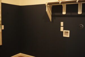 Dark blue wall with white trim and outlets.